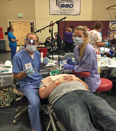 Dr. Albers and assistant with patient at 2016 COMOM dental clinic