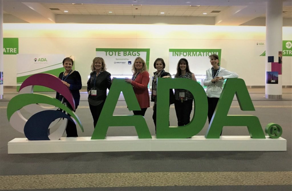 Staff posing behind 3-D ADA logo