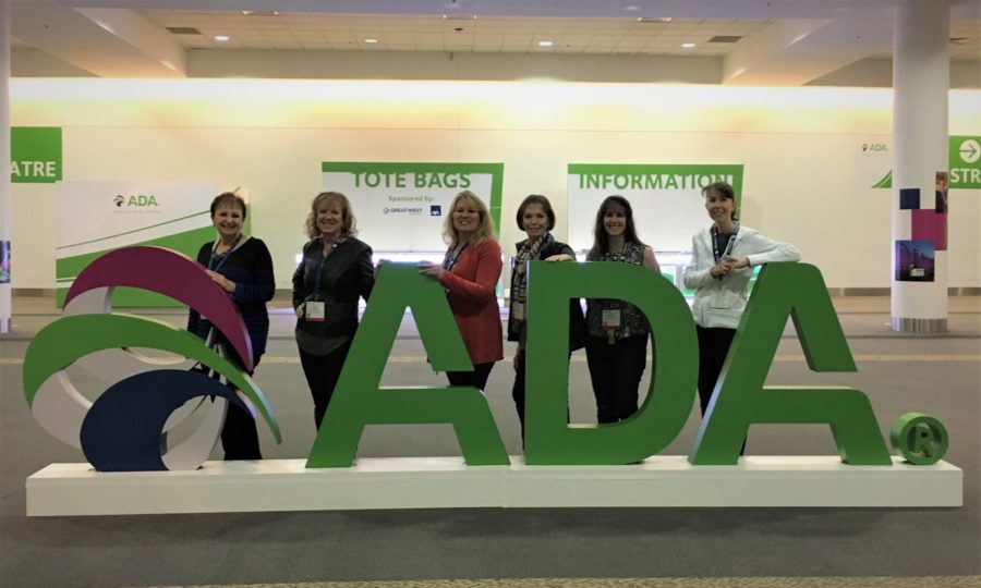 Staff posing behind 3-D ADA logo